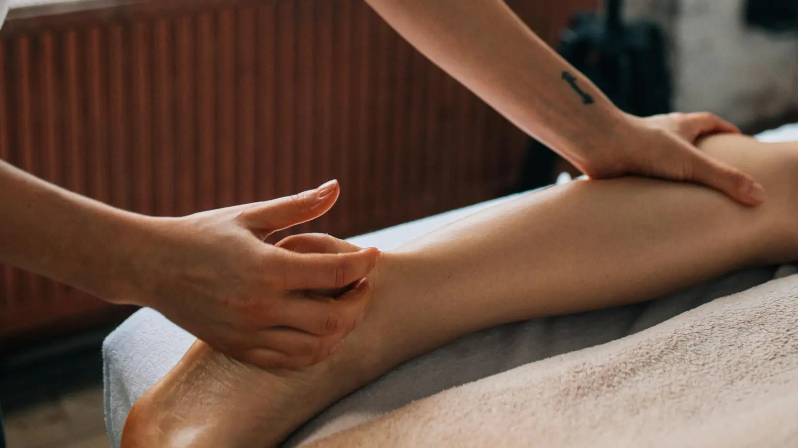 Séance de drainage lymphatique à domicile — geste précis sur la jambe en ambiance chaleureuse